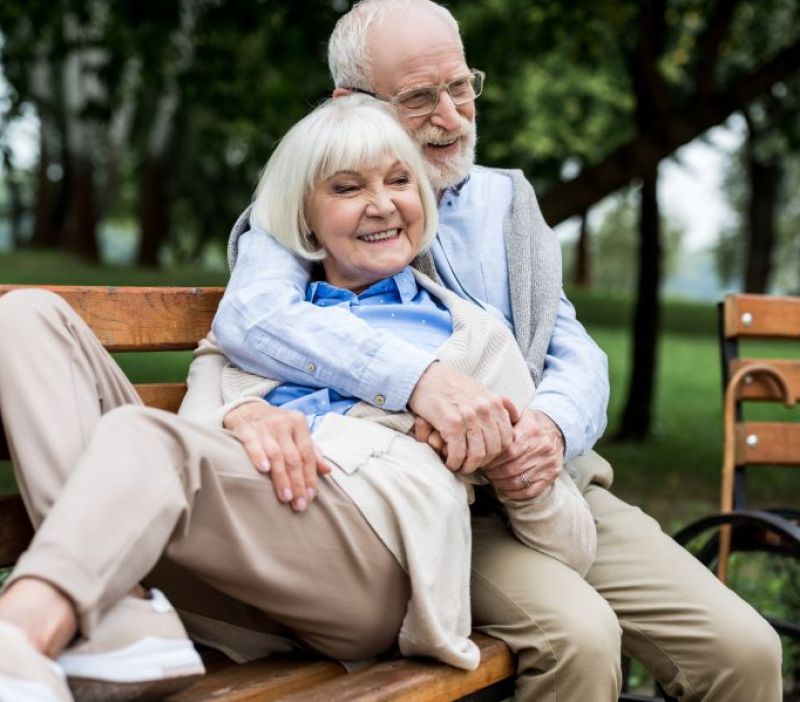 older couple sitting a bench together in the park